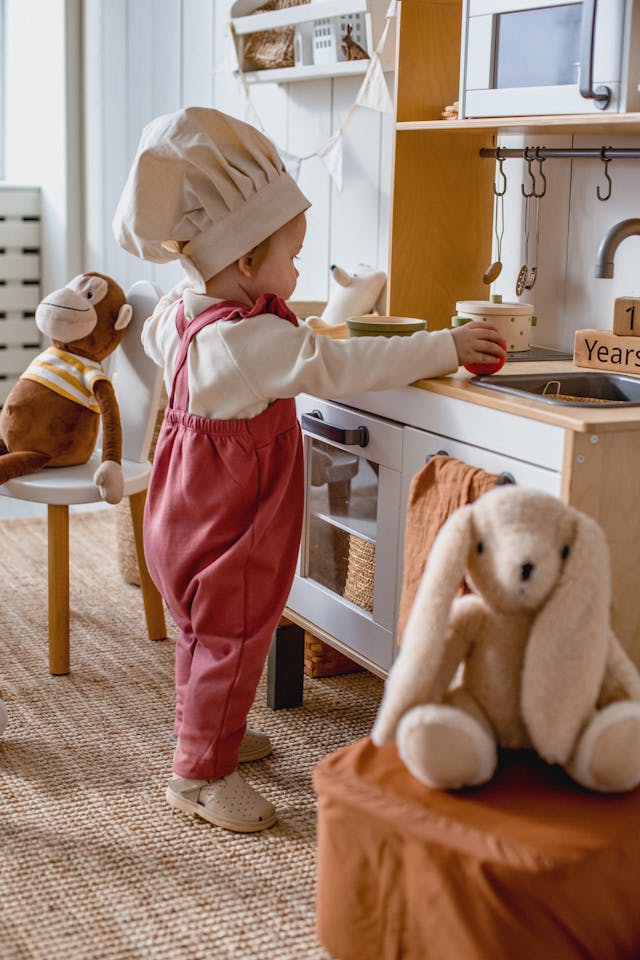 Child engaged in pretend kitchen play using toy pots and utensils