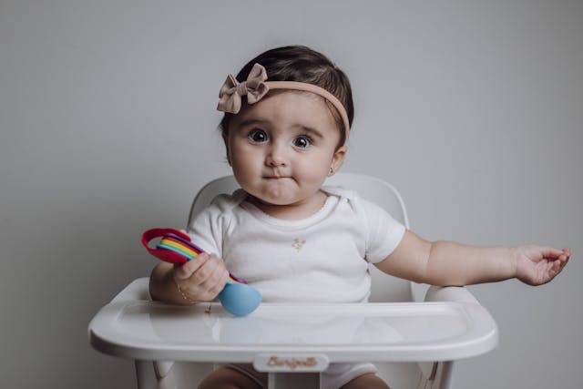 baby is sitting on a high chair waiting for food